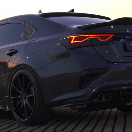 Rear view of a sleek grey car with custom performance XForce exhaust system at sunset.