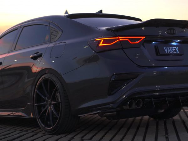 Rear view of a sleek grey car with custom performance XForce exhaust system at sunset.