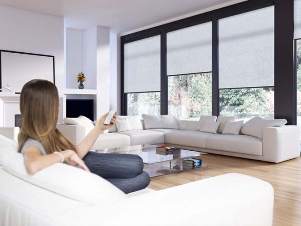 woman laying on a couch in a livingroom with big windows and automated roller blinds