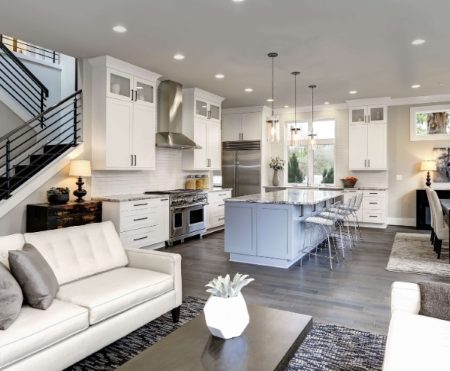 A stylish modern living room featuring a staircase and an open kitchen