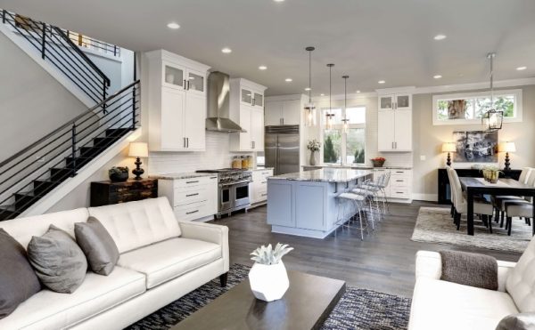 A stylish modern living room featuring a staircase and an open kitchen