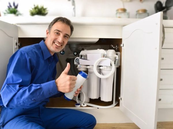 man under sink with water filters